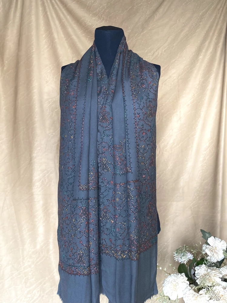 Handwoven charcoal grey cashmere scarf with intricate multicolored embroidery, displayed on a mannequin.